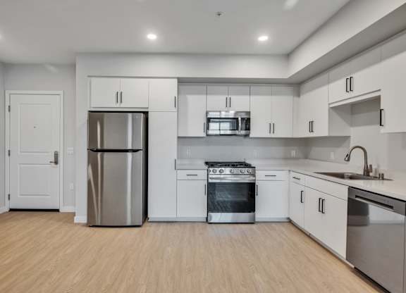 A modern kitchen with stainless steel appliances and wooden flooring.