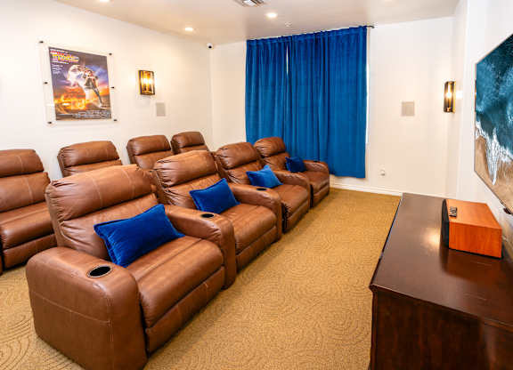 A room with brown leather chairs and a painting on the wall.
