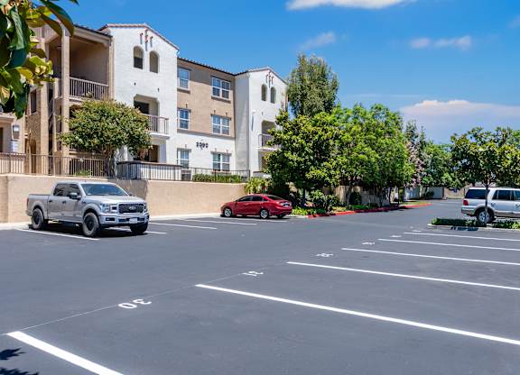 A parking lot with a red car parked in the middle.