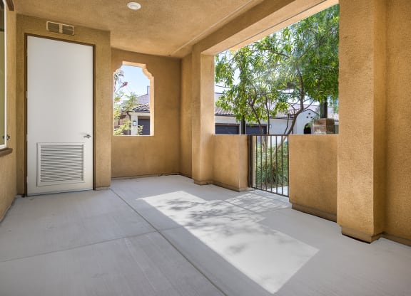 a patio with a white door and a tree in the background
