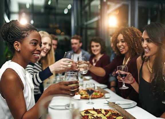 A group of people toasting with wine glasses at a dinner table.
