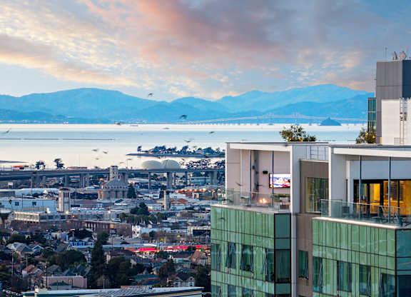 A cityscape with a large body of water and mountains in the background.