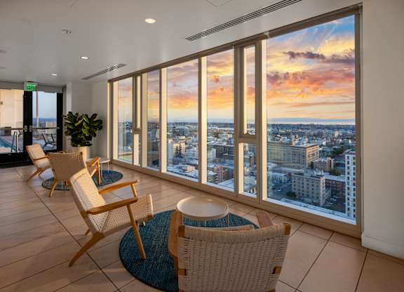 A room with a view of the cityscape at sunset.