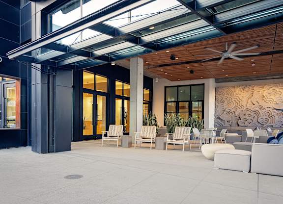 A modern outdoor seating area with white furniture and a wooden ceiling.
