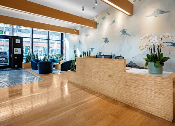A reception area with a wooden desk and a vase of flowers.