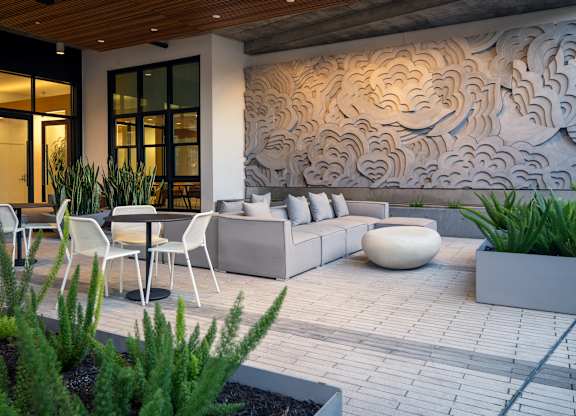 A modern outdoor seating area with a wooden ceiling and a large mural on the wall.