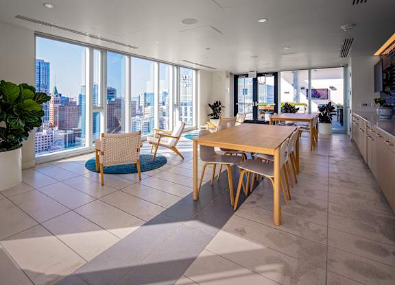 A modern kitchen with a dining table and chairs in front of a large window overlooking a cityscape.