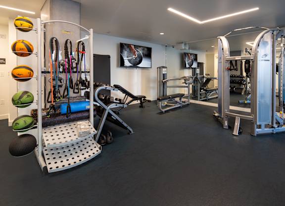 A gym with a variety of equipment including a treadmill, weights, and a bench.