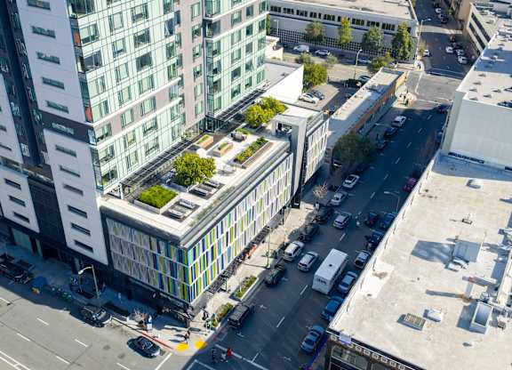 A tall building with a green roof is surrounded by other buildings and busy streets.