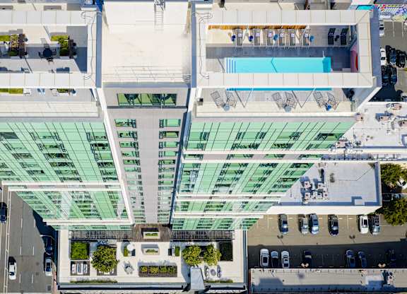 A modern building with a glass facade and a pool on the top floor.