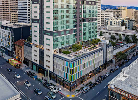 A modern glass building is situated on a busy street.