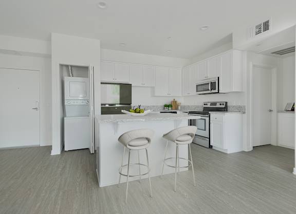 A white kitchen with a bar and stools.at 422 South Lake, California, 90057