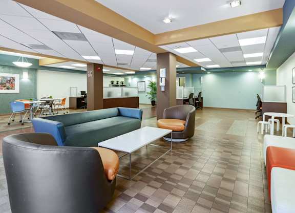 A modern office lounge with blue and grey chairs and a white table.at 6940 Sepulveda, California, 91405