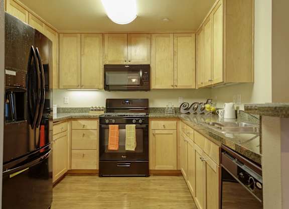 A kitchen with wooden cabinets and a black oven.at 6940 Sepulveda, Van Nuys, 91405  