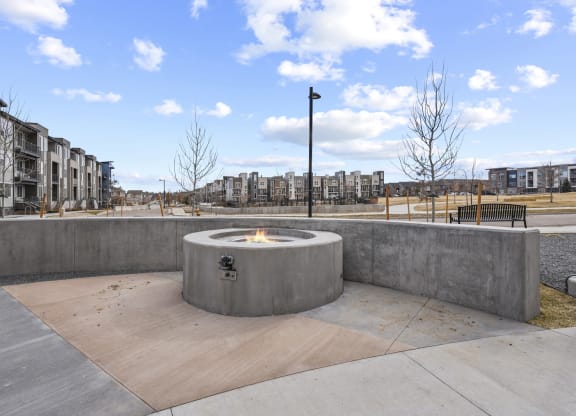 a fire pit in a park with buildings in the background at Parkside at Littleton Village, Littleton, CO