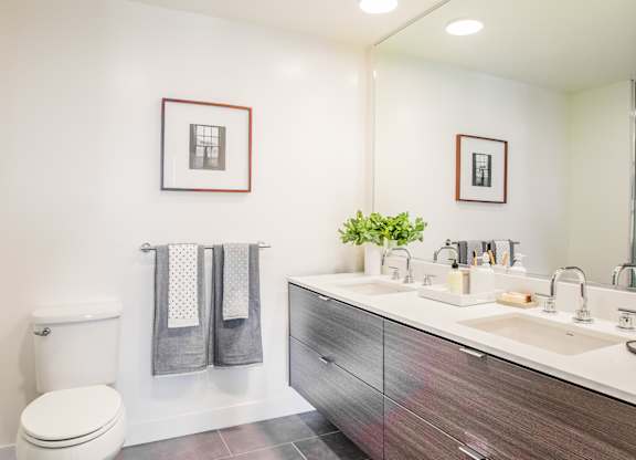 A bathroom with a toilet, sink, and mirror.at The Rise, San Francisco  