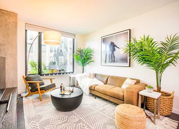 A living room with a brown couch, a coffee table, and a large window.at The Rise, San Francisco, CA  