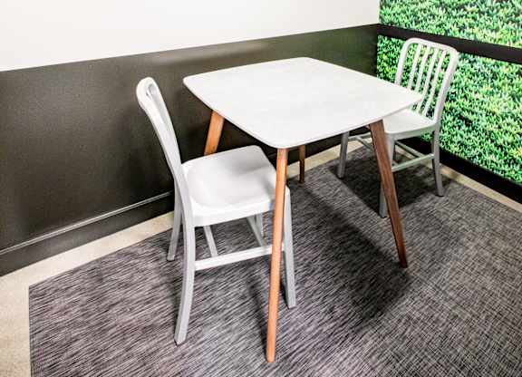 A white table with two chairs in front of a green plant wall.at The Rise, San Francisco  