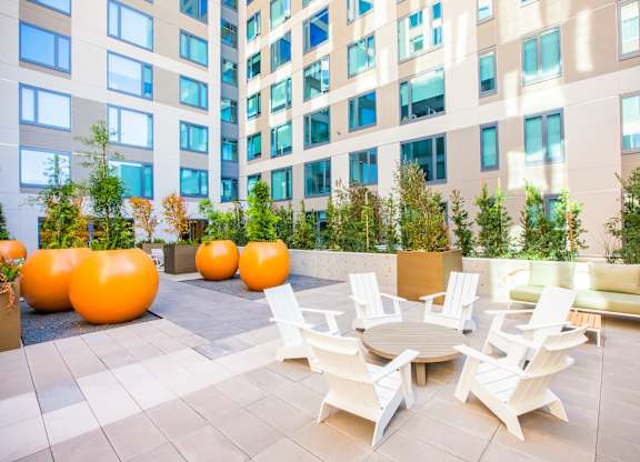 A patio with white chairs and a table with orange chairs.at The Rise, California  