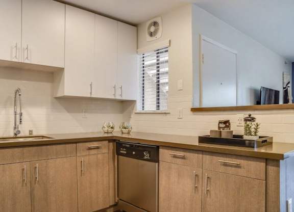 A kitchen with wooden cabinets and a stainless steel dishwasher.at Solterra At Civic Center, California, 90650-8308