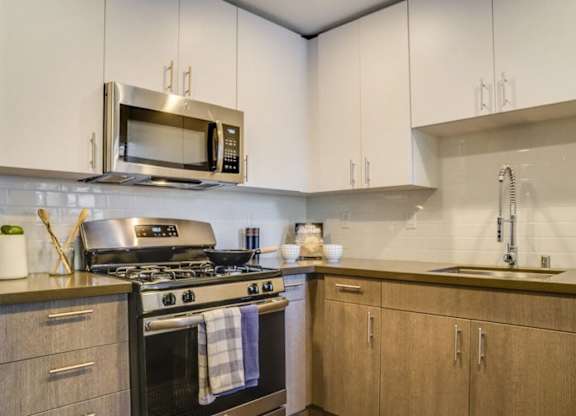 A modern kitchen with a stove, microwave, and cabinets.at Solterra At Civic Center, Norwalk  