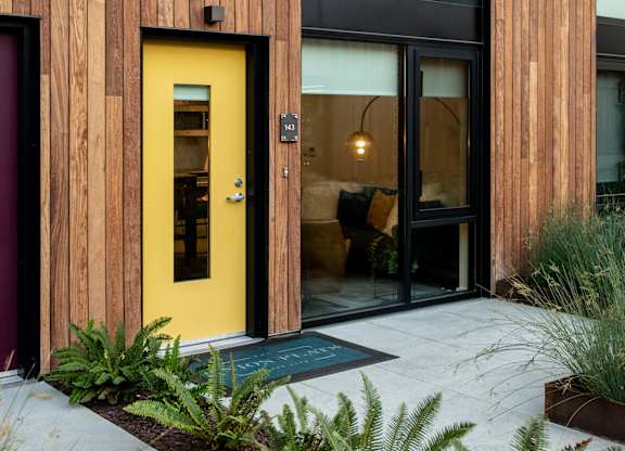 A yellow door is the centerpiece of this modern house entrance.