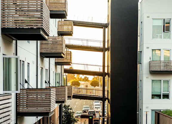 A long, narrow walkway between two buildings with a metal railing on the left and a wooden railing on the right.