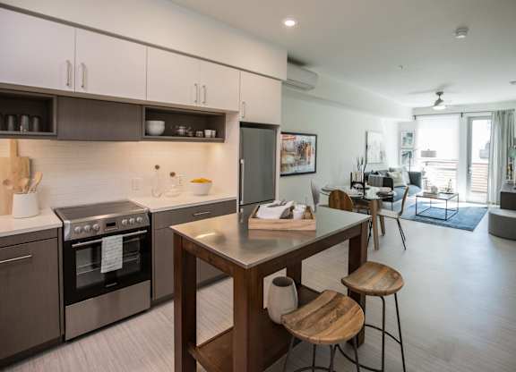 A modern kitchen with a wooden island and stools.