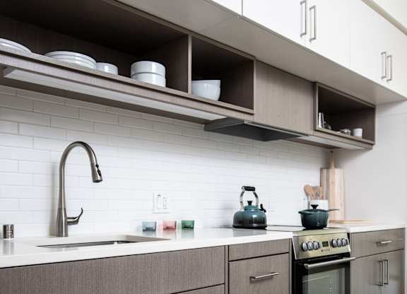 A modern kitchen with a stove, sink, and cabinets.