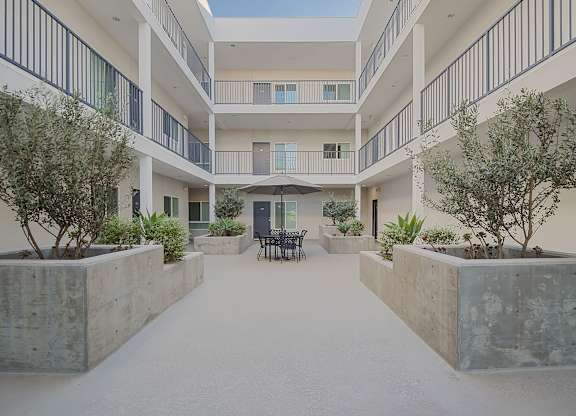 A courtyard with a concrete floor and a white building with balconies.