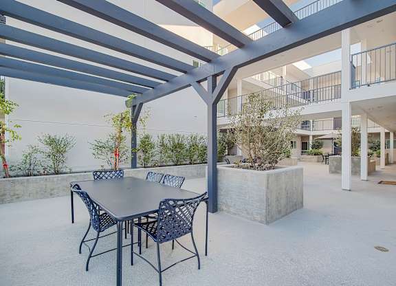 A patio with a table and chairs under a pergola.