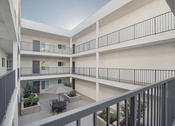 A balcony of a building with a table and chairs and an umbrella.