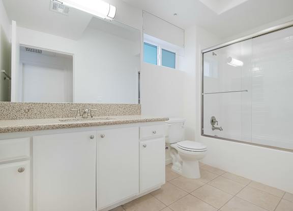 A white bathroom with a toilet, sink, and shower.
