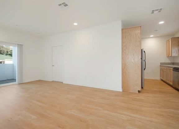 A room with wooden floors and a kitchen area with stainless steel appliances.