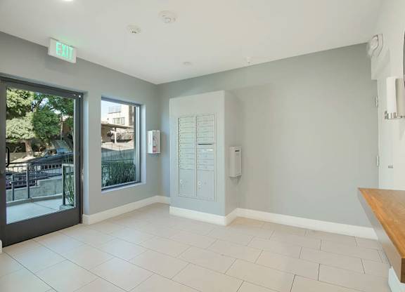 A room with a bench, a mirror, and a door with a window.