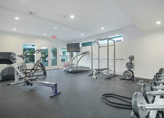 A gym with a variety of equipment including treadmills, weights, and exercise machines.