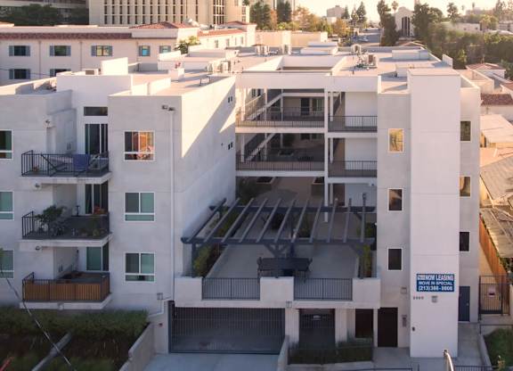 A white apartment building with a parking garage in front.