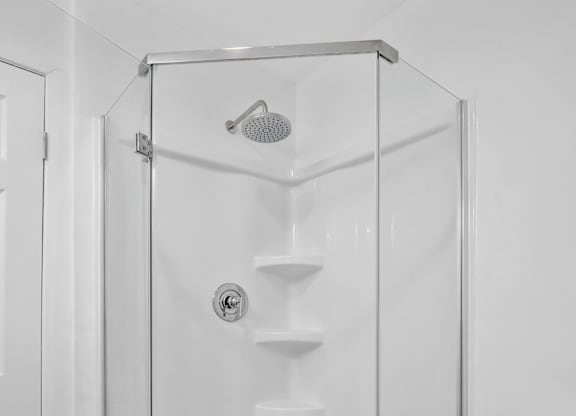 A white bathroom with a walk in shower at Verandas Apartments, West Covina, California