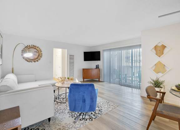 A living room with a white sofa, a blue chair, and a wooden cabinet at Verandas Apartments, California, 91791