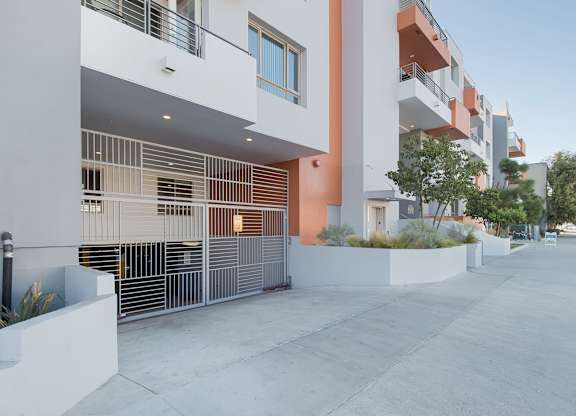A modern building with a white and orange facade and a metal fence at Woodley Sara Apartment, California, 91406