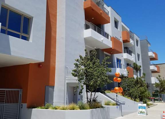 A modern apartment building with orange and white balconies at Woodley Sara Apartment, Van Nuys