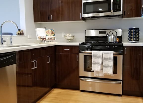 A modern kitchen with wooden cabinets and stainless steel appliances at Woodley Sara Apartment, California, 91406