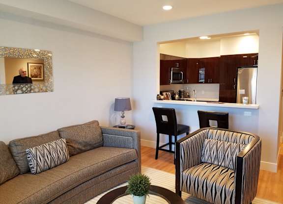 A living room with a brown couch, a striped chair, and a coffee table at Woodley Sara Apartment, Van Nuys, California