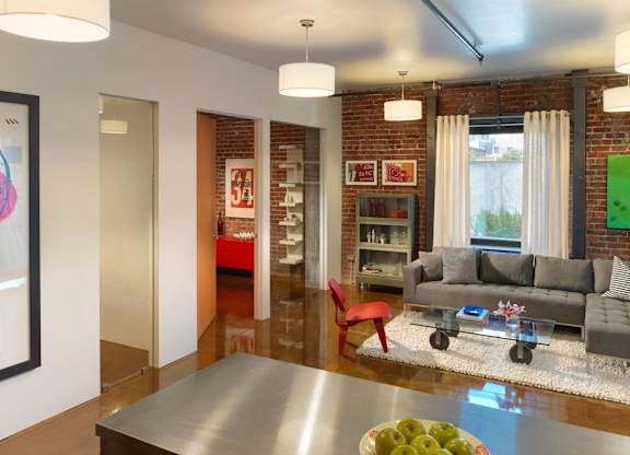 A modern living room with a grey couch and a red chair.