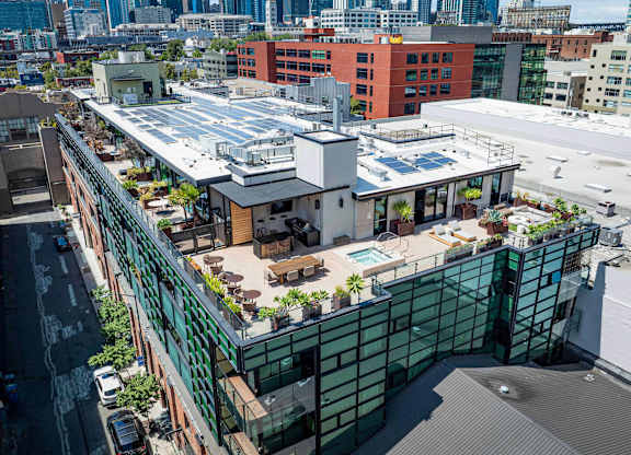 A rooftop patio with a pool and seating area.