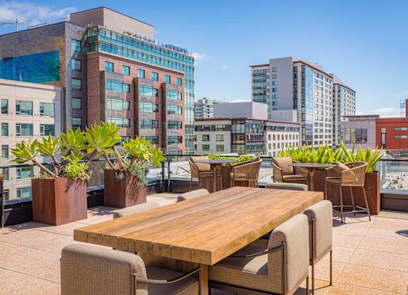 A wooden table surrounded by chairs on a rooftop patio.