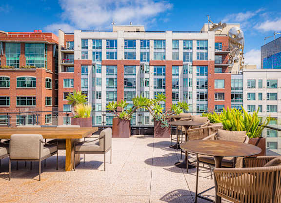 A patio with tables and chairs is surrounded by buildings.