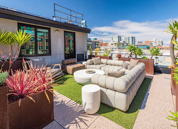 A patio with a white couch and a green plant.