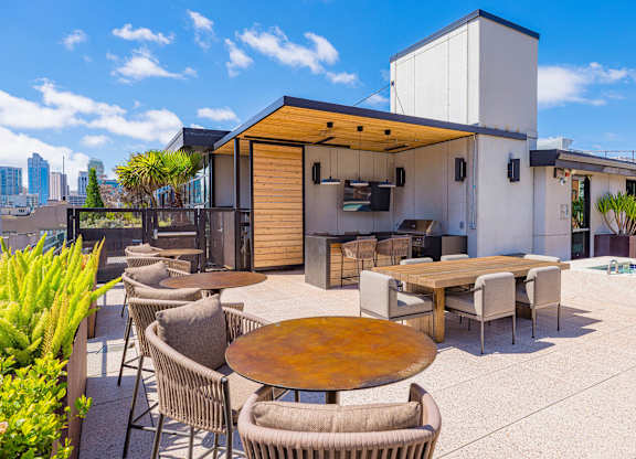 A modern outdoor dining area with a wooden table surrounded by chairs.