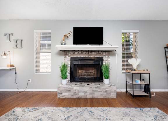 A living room with a fireplace and a flat screen TV mounted above it.